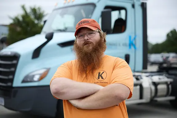 A man in a orange shirt standing in front of a truck