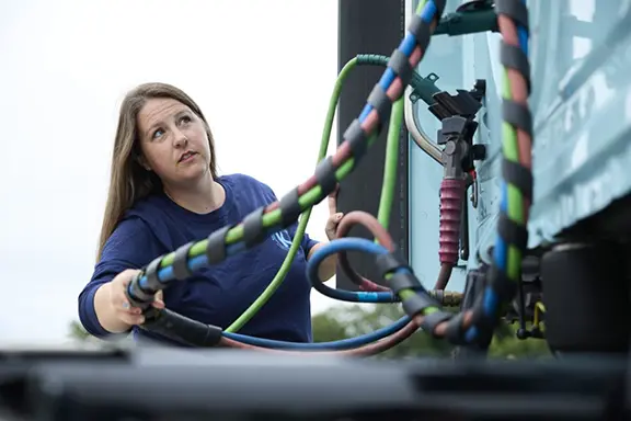 A woman checking the lines on a semi truck