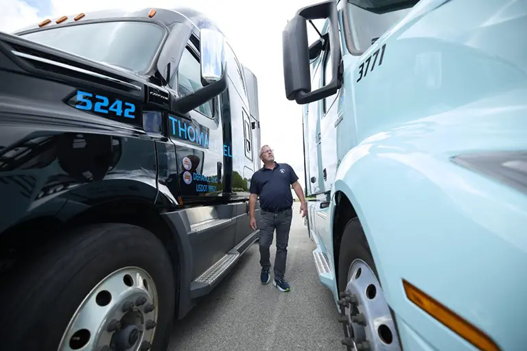 A man walking, inspecting between two semi trucks